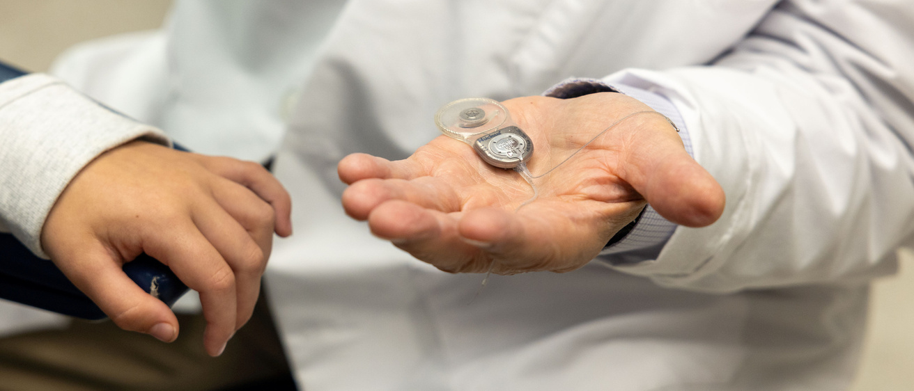 Bruce J. Gantz, MD, shows a cochlear implant to a simulated pediatric patient